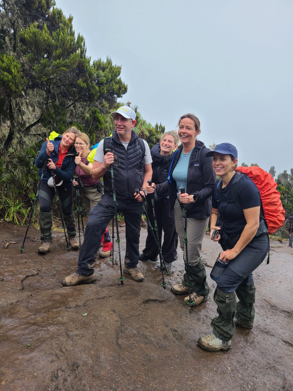 Smiling Kilimanjaro trekking team on a wet mountain trail